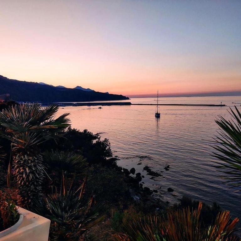 a sunset over a body of water with a sail boat at Le Camere della Campana in Castellammare del Golfo