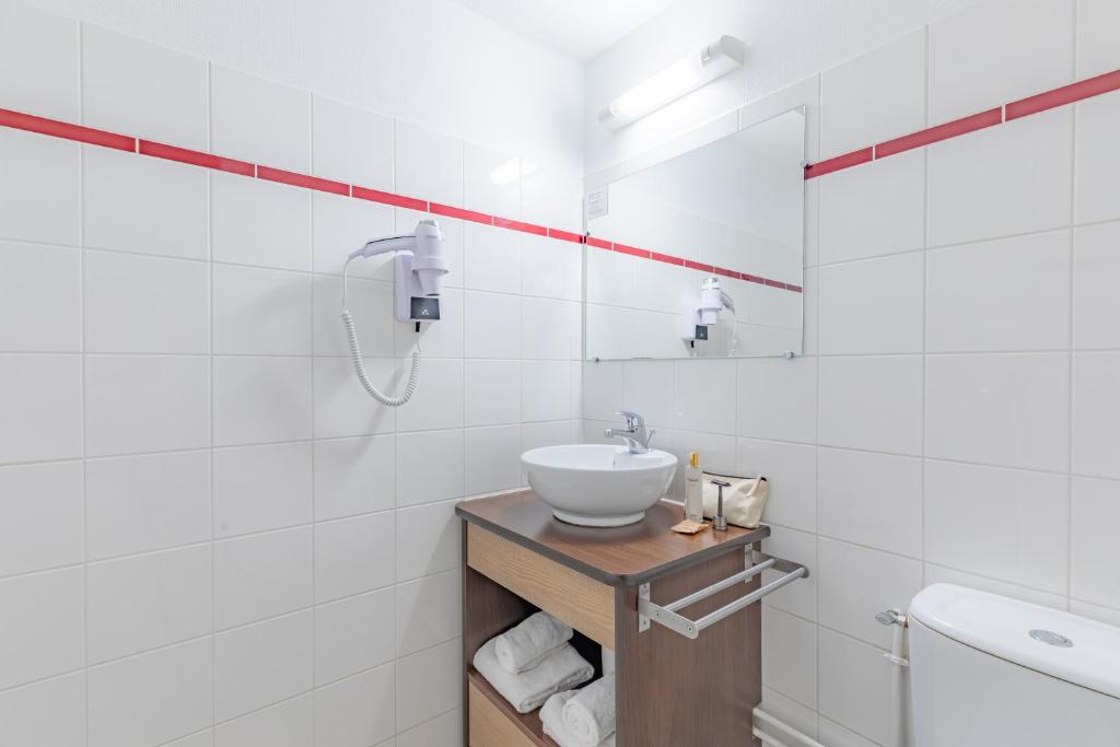 a white bathroom with a sink and a mirror at Appart&#39;City Confort Pau Centre in Pau