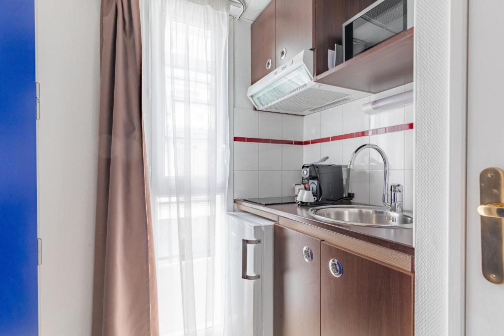 a small kitchen with a sink and a window at Appart&#39;City Confort Pau Centre in Pau