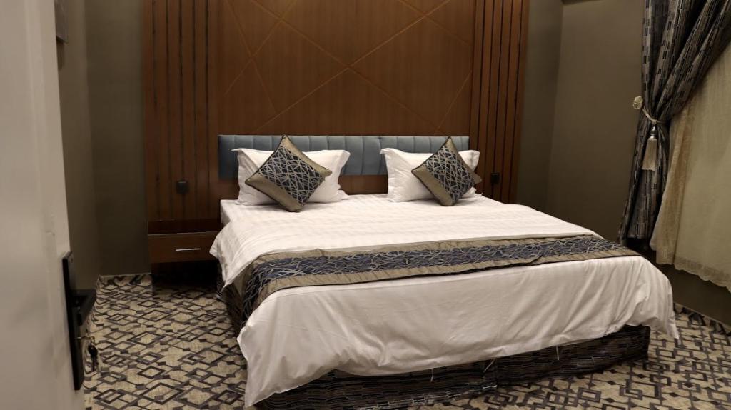 a bedroom with a large bed with white sheets and pillows at شقق فاتوران الفاخره in Al Madinah