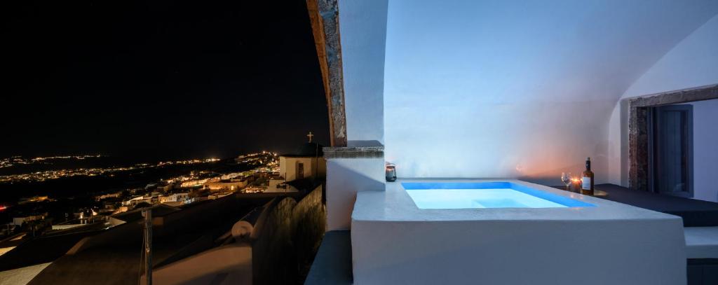 a bath tub with a view of a city at night at Pyrgos Cave Suites in Pirgos