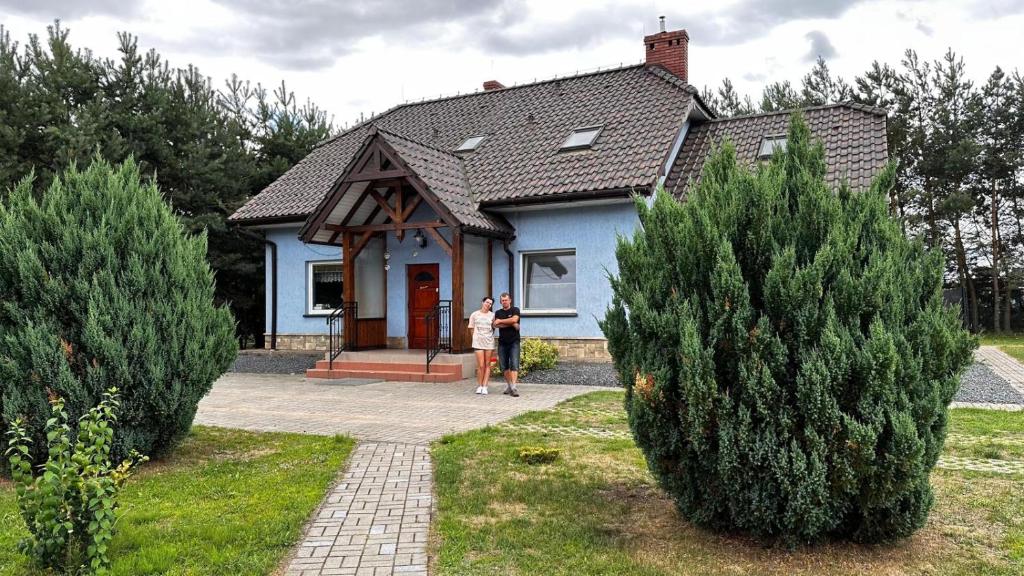 2 personnes debout devant une maison bleue dans l'établissement Agroturystyka Włochate Ranczo, 