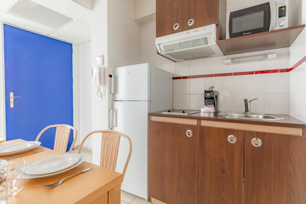 a kitchen with a table and a white refrigerator at Appart&#39;City Confort Pau Centre in Pau