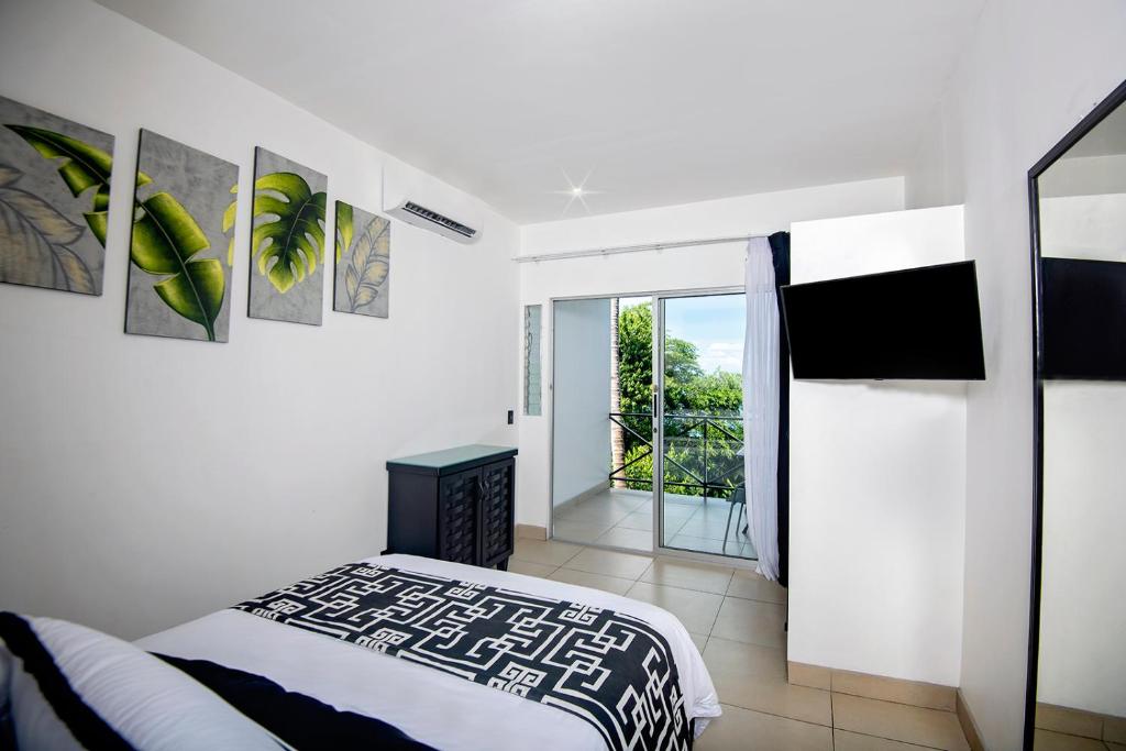 a white bedroom with a bed and a balcony at Villa Roca Boutique Resort & Suites - ADULT ONLY in Manuel Antonio