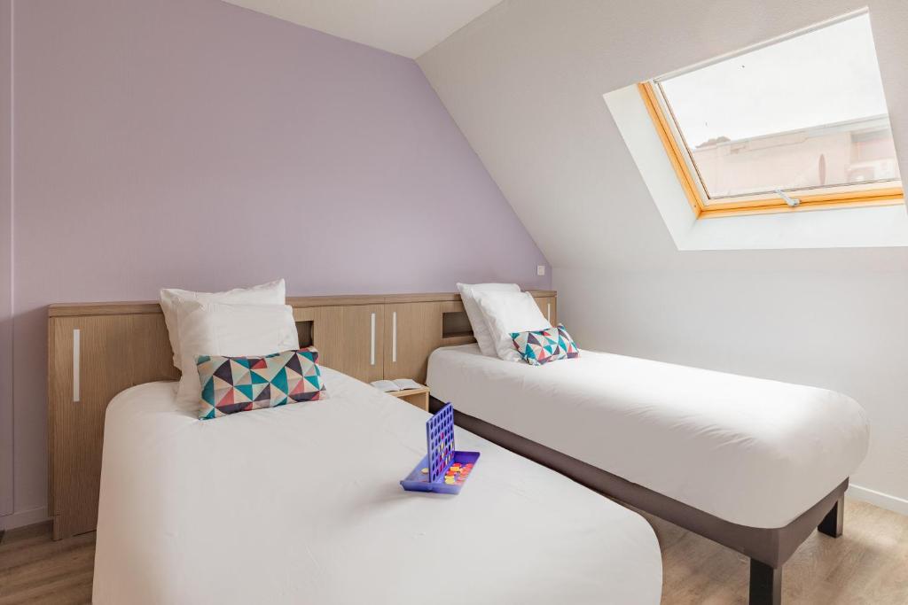 two beds in a room with a window at Appart&#39;City Confort Pau Centre in Pau