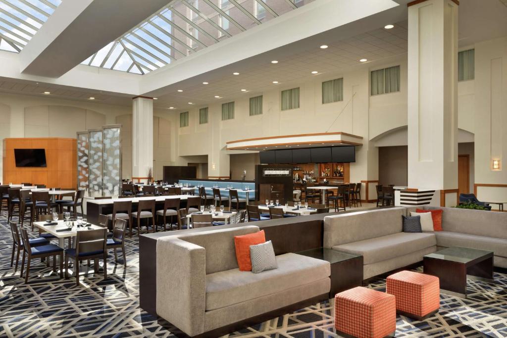 a hotel lobby with a restaurant with tables and chairs at Embassy Suites Boston at Logan Airport in Boston