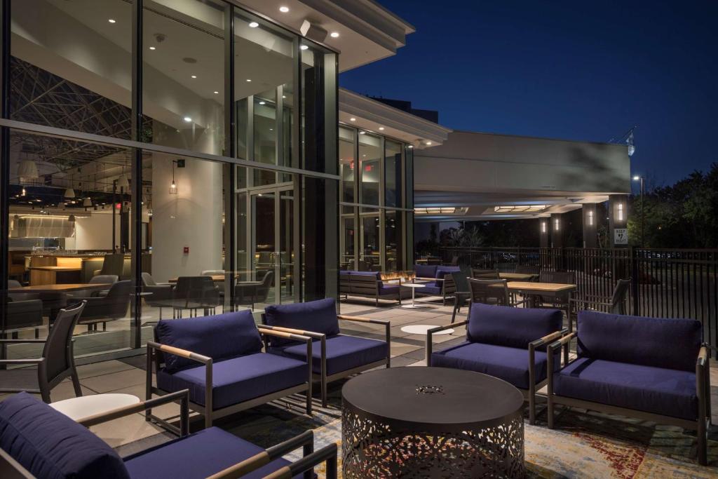 a patio with blue chairs and tables in front of a building at Hilton Boston-Woburn in Woburn