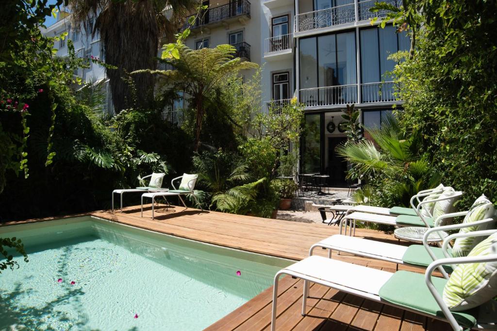een terras met stoelen en een zwembad met een gebouw bij Casa do Barao in Lissabon