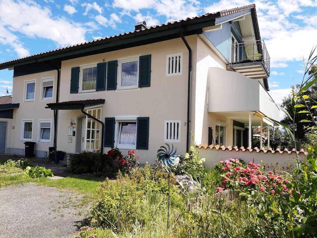Casa blanca con flores y ventanas con persianas negras en Ferienwohnung Pickenhan, en Scheidegg