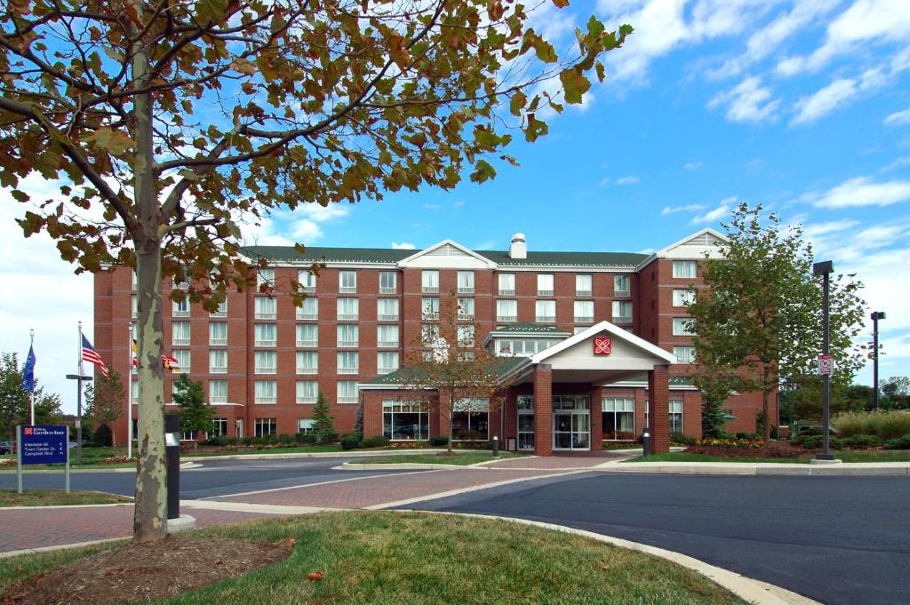 a large red building with a tree in front of it at Hilton Garden Inn White Marsh in White Marsh