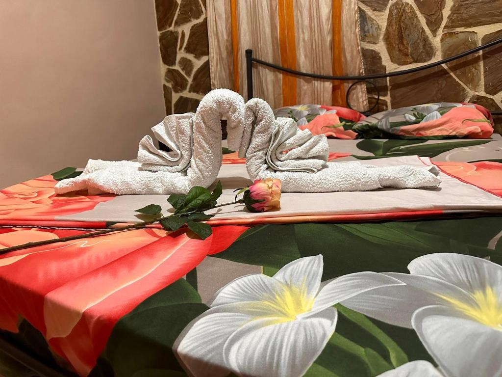 two beds with towels and flowers on top of them at Nice Holiday House in Piraeus