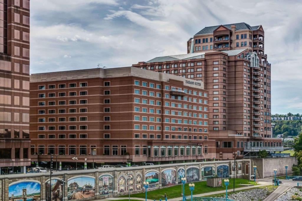 a large brown building with two tall buildings at Embassy Suites Cincinnati - RiverCenter in Covington