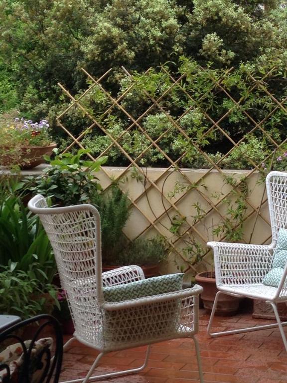 three wicker chairs sitting on a patio with plants at Apartments Quiet In The City in Florence