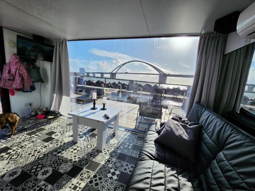 ein Wohnzimmer mit einem Sofa und einem großen Fenster in der Unterkunft Houseboat of Grimm in Fehmarn