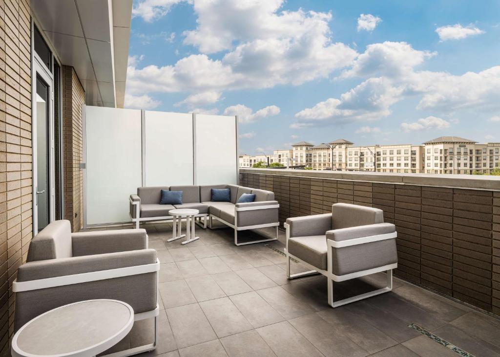 a balcony with chairs and tables on a building at Canopy By Hilton Dallas Frisco Station in Frisco