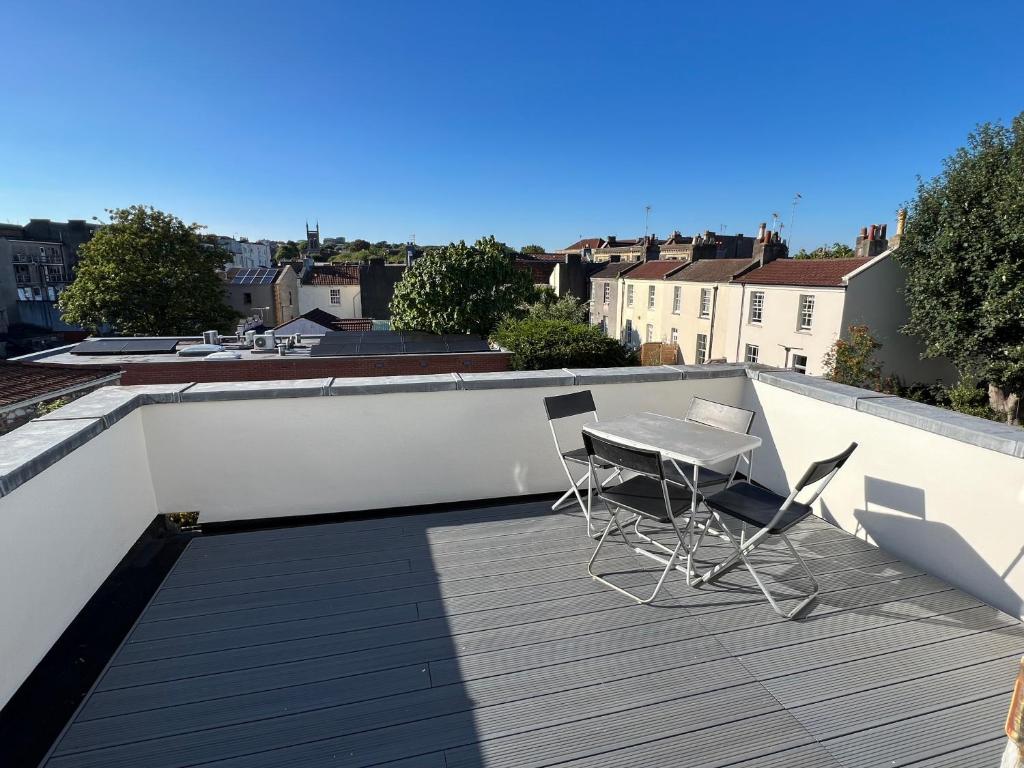 a balcony with a table and chairs on a roof at 3 bed penthouse flat with conservatory & roof terrace - city views in Bristol