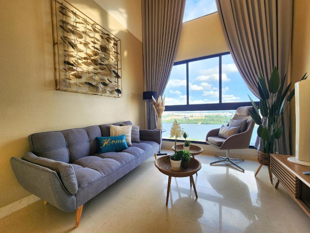 - un salon avec un canapé bleu et une grande fenêtre dans l'établissement Loft Suite Seaview Near Johor Bahru Custom 7 pax, à Johor Bahru