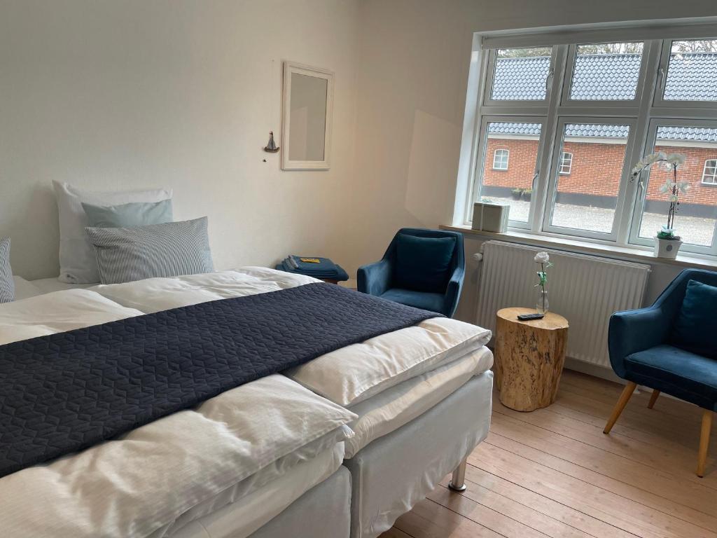 um quarto com uma cama e duas cadeiras azuis em Thyholm B&B em Thyholm