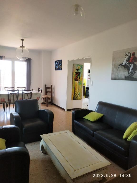 un salon avec un canapé noir et une table dans l'établissement Ondine Vacances, à Six-Fours-les-Plages