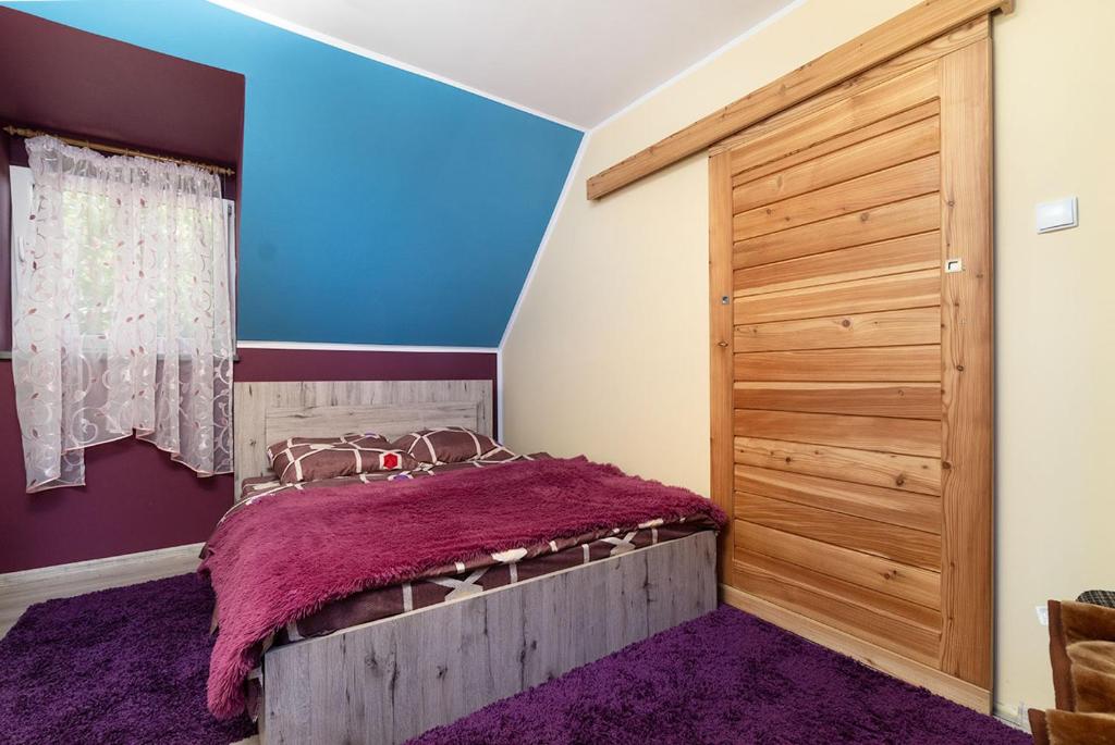 1 dormitorio con 1 cama y puerta de madera en Szczęśliwe Ranczo nad Doliną 539-279-448, en Bereżnica Wyżna