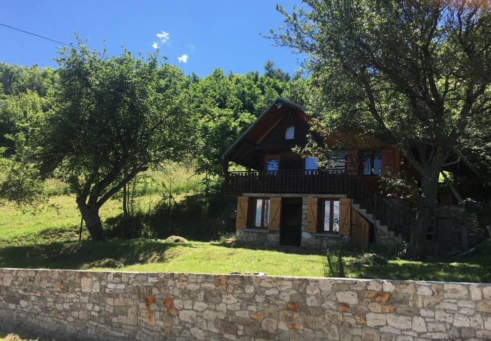 een klein huis met een stenen muur en bomen bij Chalet accueillant pour des vacances reposantes in Jarrier
