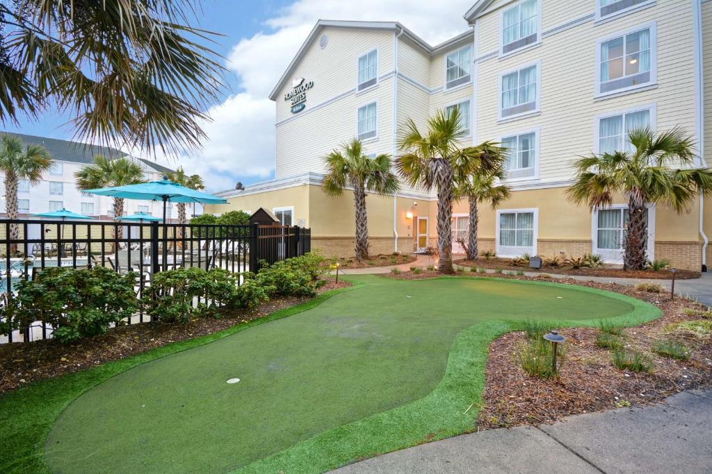 un parcours de golf en face d'un bâtiment avec des palmiers dans l'établissement Homewood Suites by Hilton Wilmington/Mayfaire, NC, à Wilmington