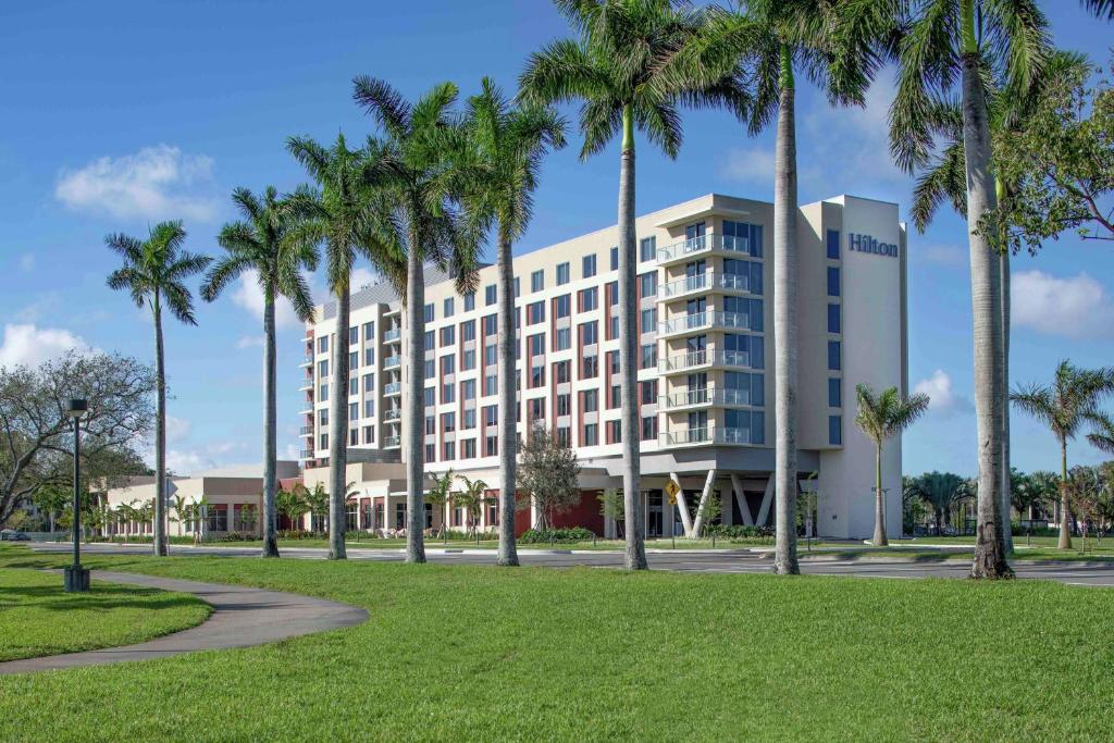 un bâtiment avec des palmiers en face d'un parc dans l'établissement Hilton Miami Dadeland, à South Miami