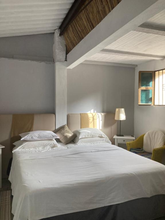 um quarto com uma grande cama branca e 2 cadeiras em Yoga Farm em Tavira