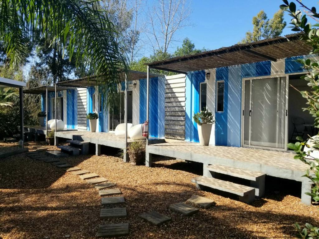 uma casa azul com bancos brancos em frente em Squania Suite Container & Monoambientes em Termas del Daymán