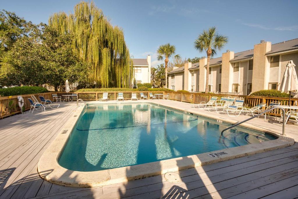 a swimming pool with chairs and a building at St Simons Island Condo with Deck and Outdoor Shower in Saint Simon Mills