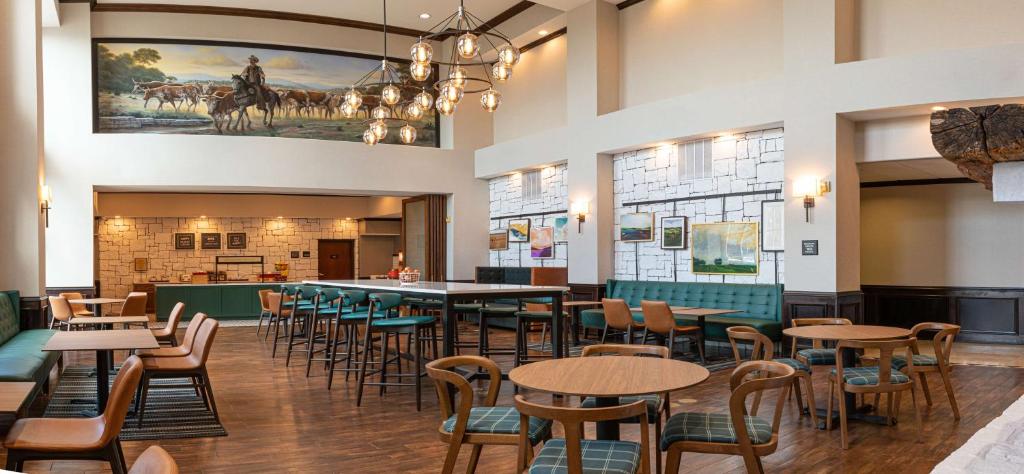 a restaurant with tables and chairs and a large painting on the wall at Hampton Inn & Suites Boerne in Boerne