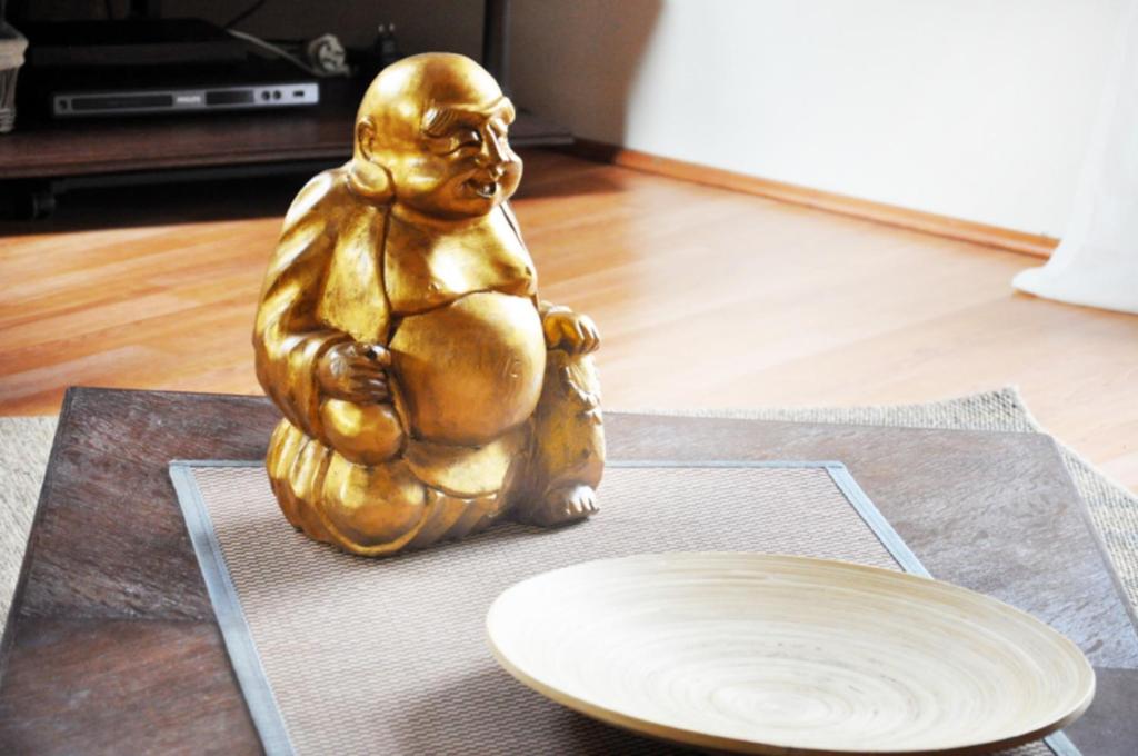 una estatua de oro sentada en el suelo junto a un plato en Point Escale, en Lontzen