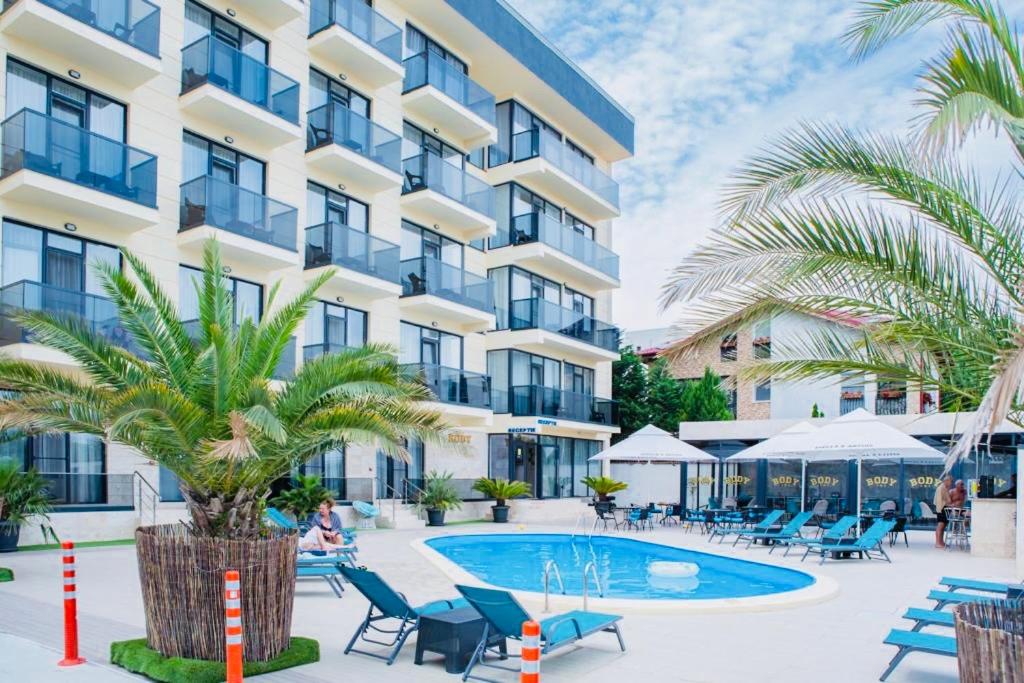 - une vue sur l'extérieur d'un hôtel avec une piscine et des palmiers dans l'établissement Body Hotel, à Mamaia Nord – Năvodari