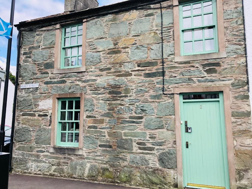 an old stone building with a door and two windows at 2 Fleet Street in Castle Douglas