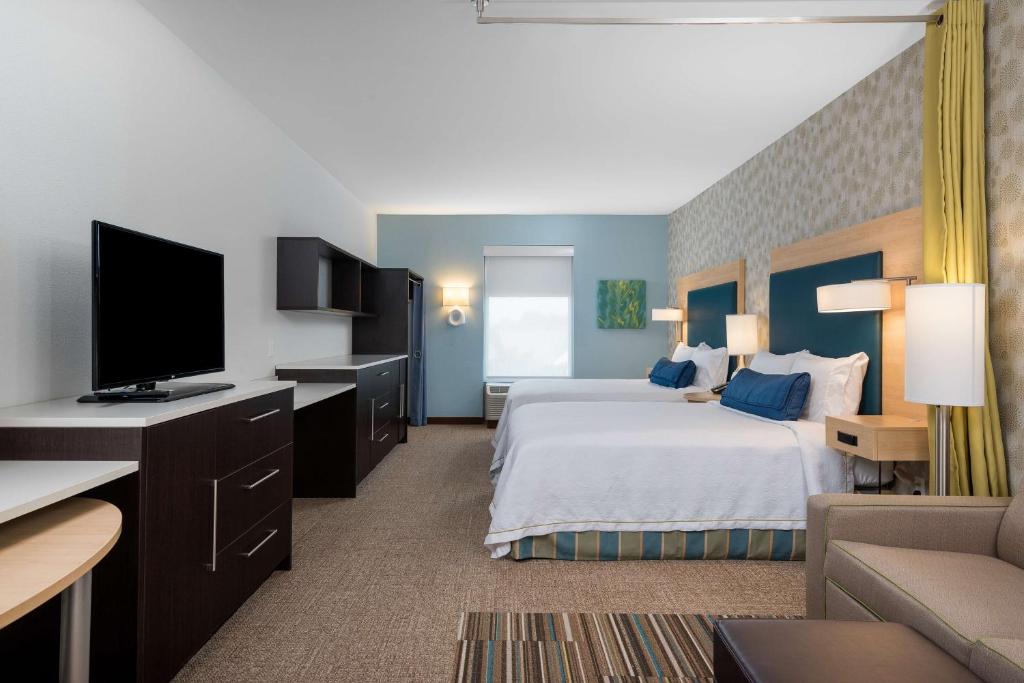 a hotel room with a bed and a flat screen tv at Home2 Suites by Hilton Charlotte University Research Park in Charlotte