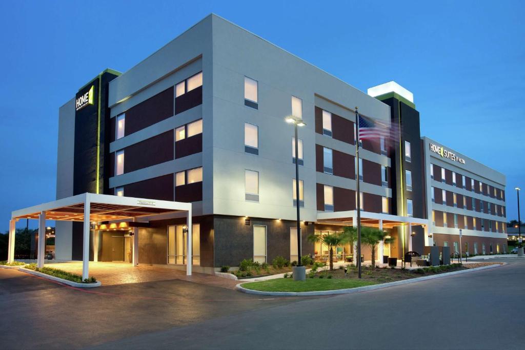 un edificio con una bandera americana delante de él en Home2 Suites by Hilton San Antonio Airport, TX en San Antonio