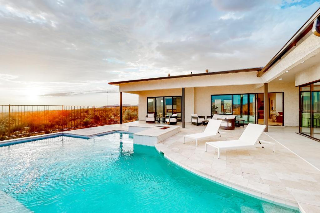 una piscina con sillas blancas y una casa en The Sunrise Perch, en Tortolita