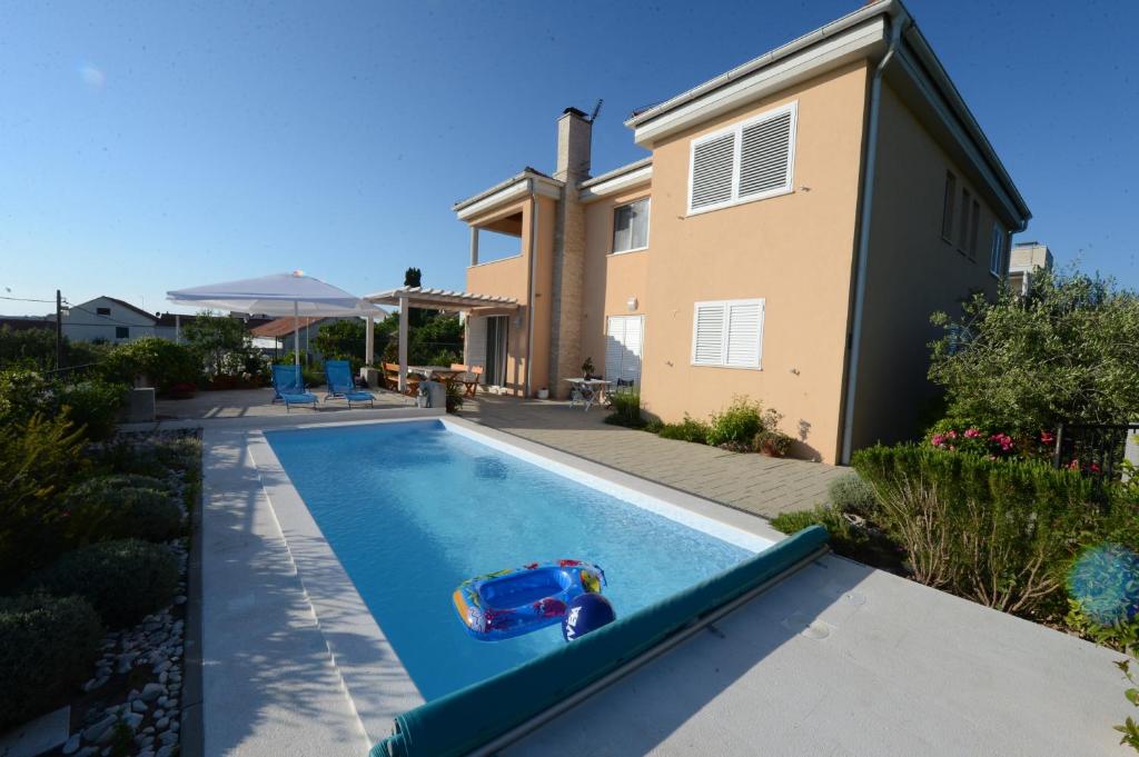 a toy car in a swimming pool in front of a house at Apartment Mara in Petrcane
