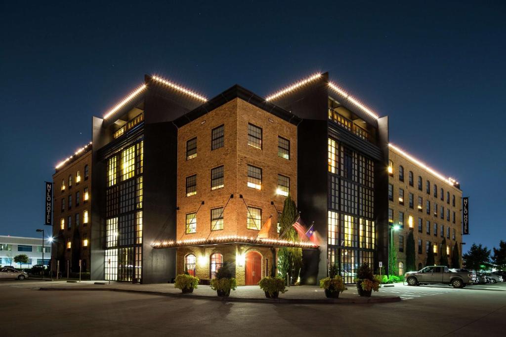 un grande edificio con luci accese di notte di NYLO Dallas Plano Hotel, Tapestry Collection by Hilton a Plano