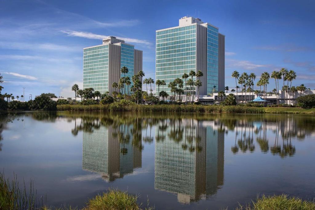 dwa wysokie budynki znajdują odbicie w zbiorniku wodnym w obiekcie DoubleTree by Hilton at the Entrance to Universal Orlando w Orlando