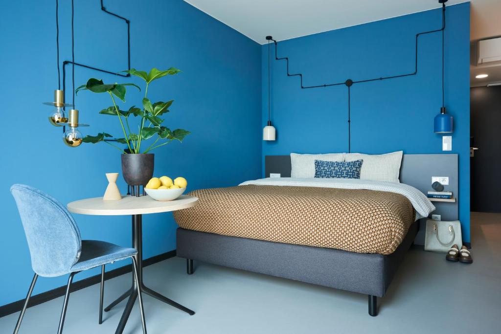 um quarto azul com uma cama, uma mesa e uma cadeira em Nena Apartments Bochum City em Bochum