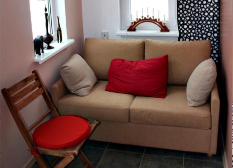 un sofá marrón con 2 almohadas rojas y una silla en MaaRitza Holiday Cottage en Türi