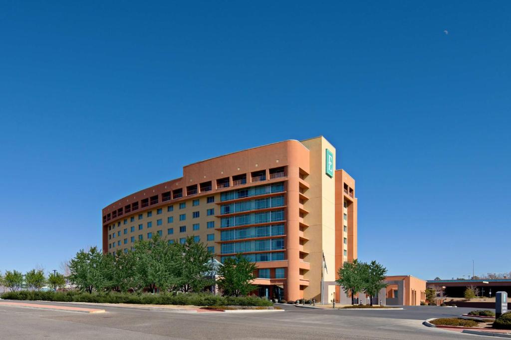 un grand immeuble de bureaux avec une route devant lui dans l'établissement Embassy Suites by Hilton Albuquerque, à Albuquerque