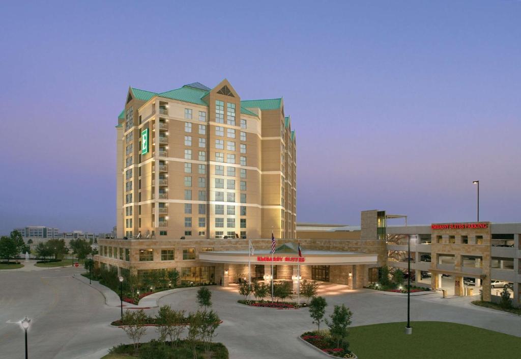 弗赖拉辛Embassy Suites by Hilton Dallas Frisco Hotel & Convention Center的一座大楼，前面有一个停车场