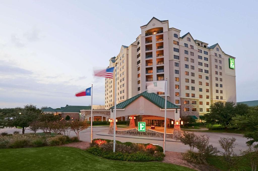 a hotel building with flags in front of it at Embassy Suites Dallas - DFW Airport North in Grapevine