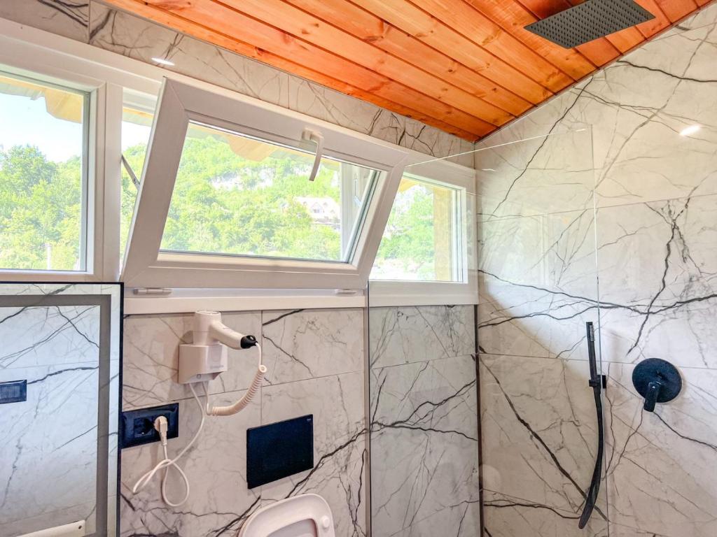 a bathroom with a shower with a sink and a window at Villa Logu in Theth