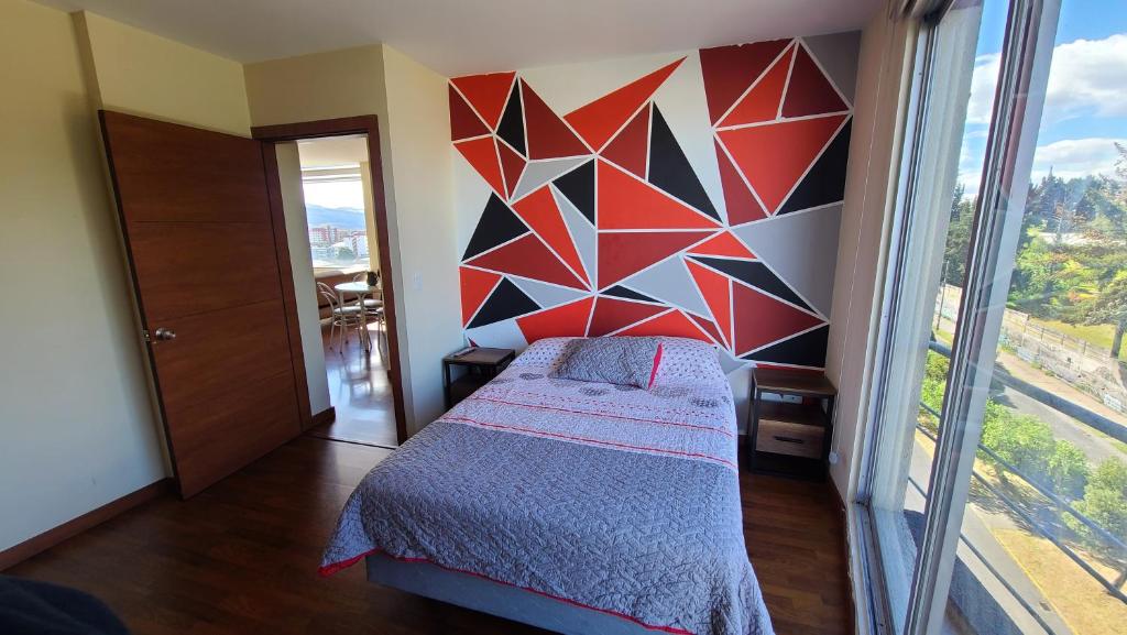 um quarto com uma cama com uma parede geométrica em Departamento Privado una habitación y balcón Sector Solca y Embajada EEUU em Quito