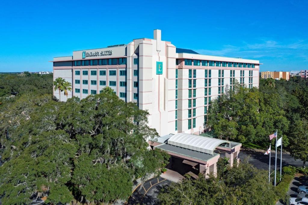 a large white building with a green sign on it at Embassy Suites by Hilton Tampa USF Near Busch Gardens in Tampa