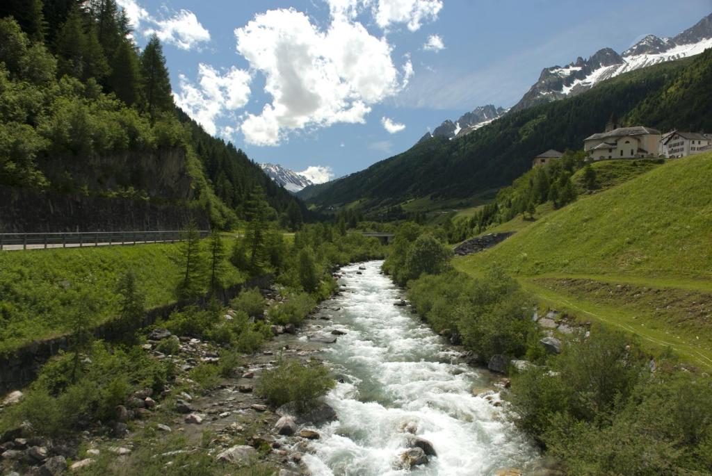 a river in a valley next to a mountain at ECONOMY b&b in Bedretto