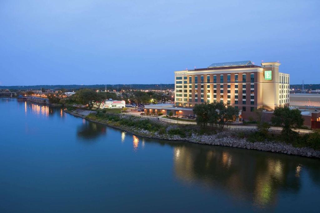 un gran edificio junto a un río con un edificio en Embassy Suites East Peoria Hotel and Riverfront Conference Center, en Peoria